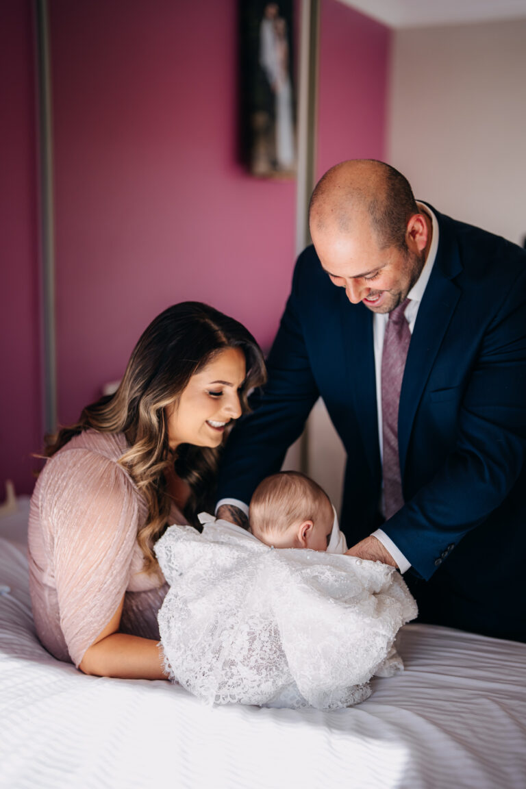 God Parents dressing their baby in her christening gown before the ceremony