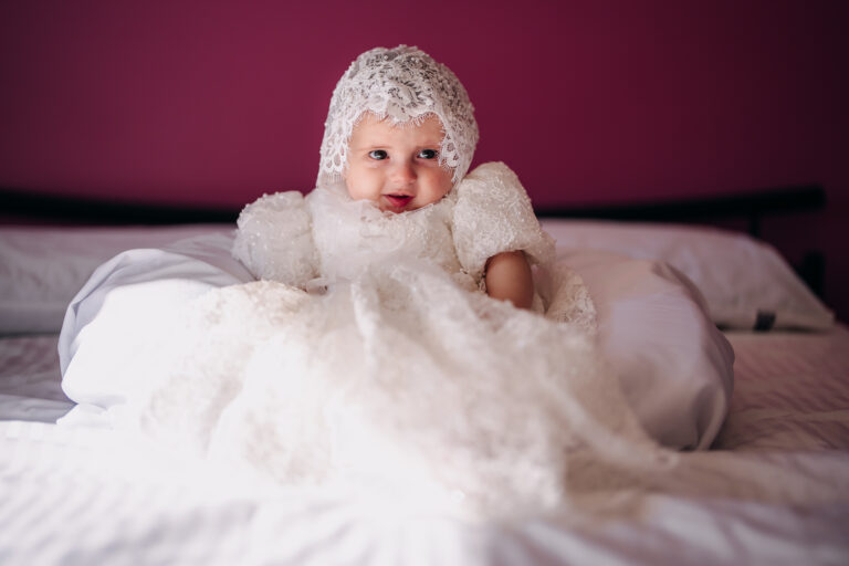 Baby wearing an elegant white christening gown before her baptism