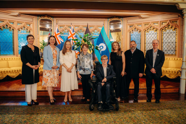 Formal group photograph of event guests in front of Australian flags at Government House Sydney