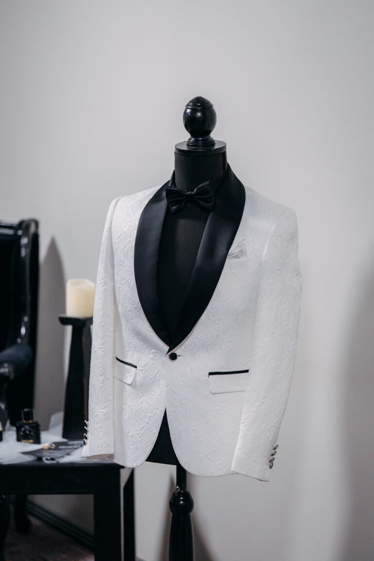 White groom's wedding tuxedo displayed on a mannequin during wedding preparations.