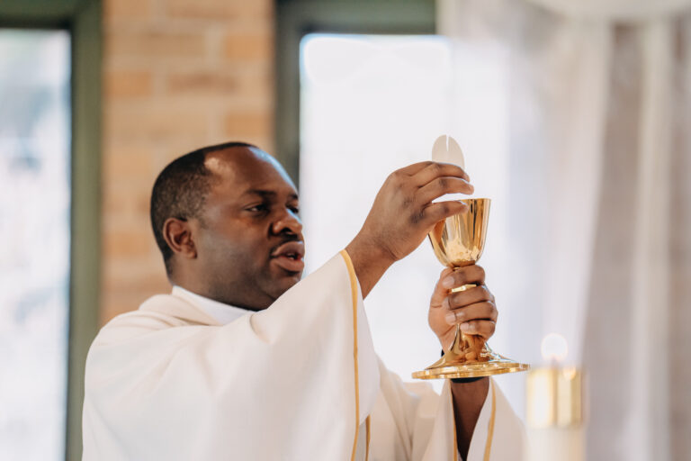 Priest raising the ceremonial chalice during Jordan and Shakira's church wedding.