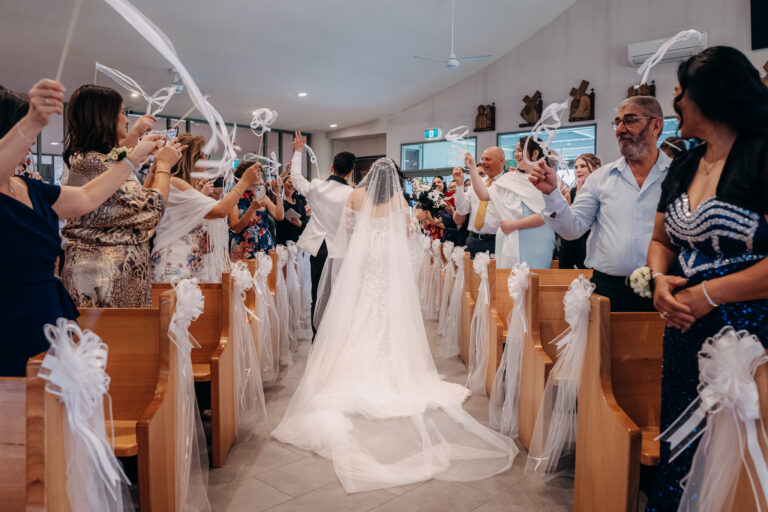 Bride and groom walking down the church aisle as guests celebrate their wedding.