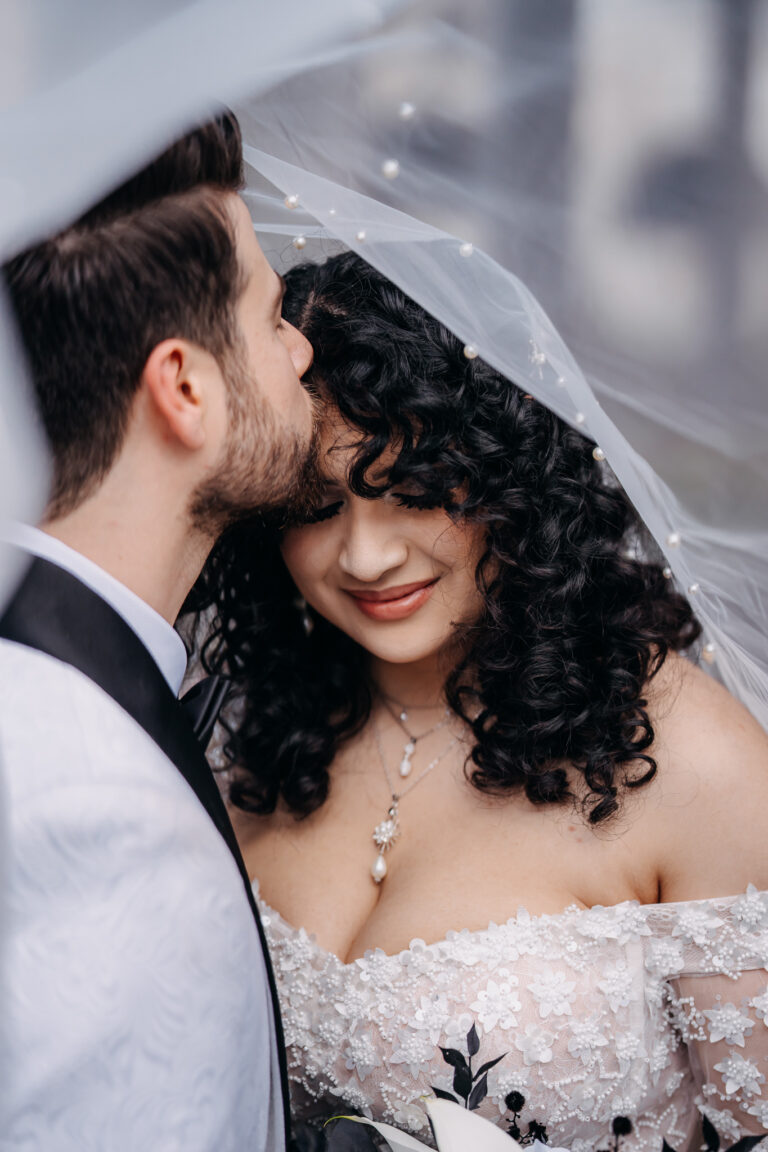 Romantic close-up of Jordan and Shakira smiling together beneath the bridal veil.