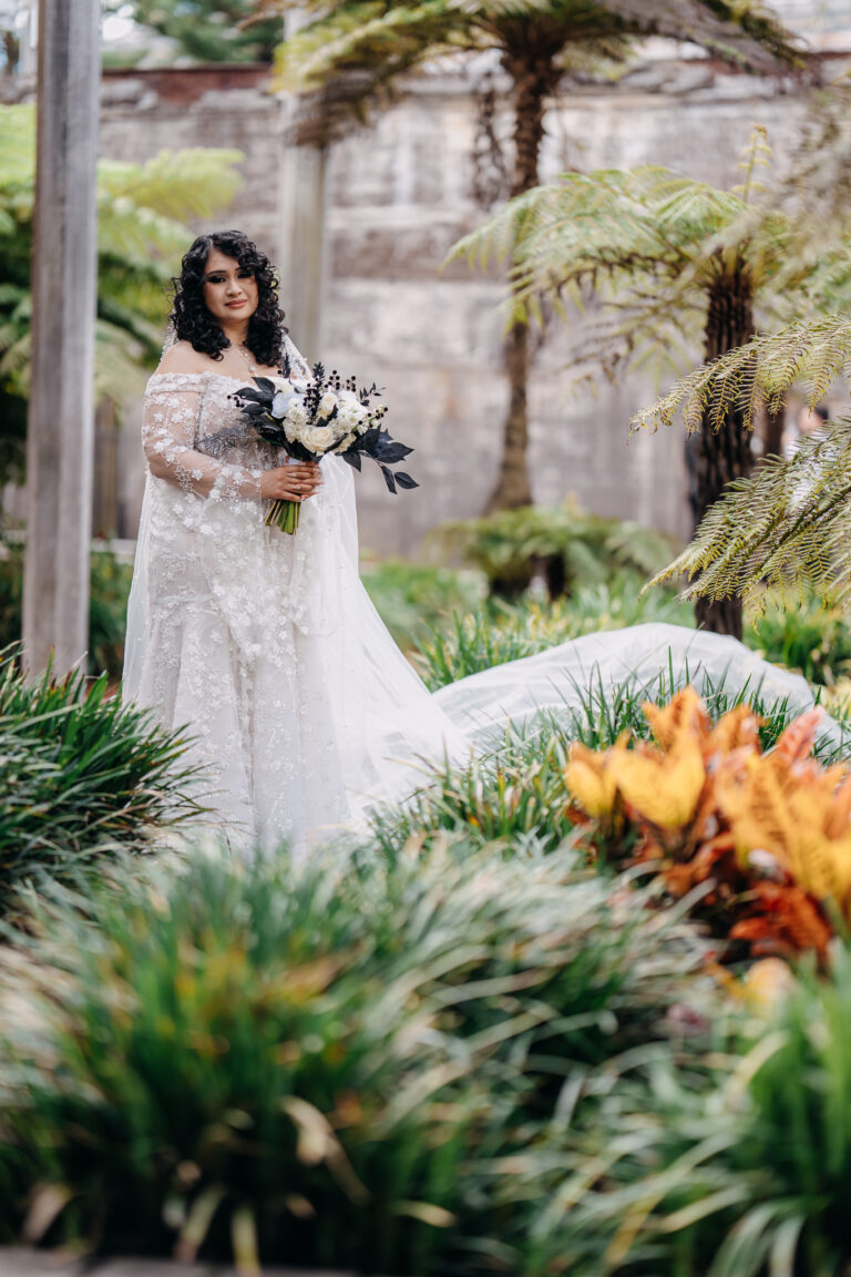 Elegant bridal portrait of Shakira holding her bouquet in a lush garden setting.