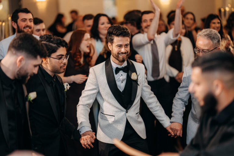 Groom Jordan celebrating with friends and family on the wedding dance floor.
