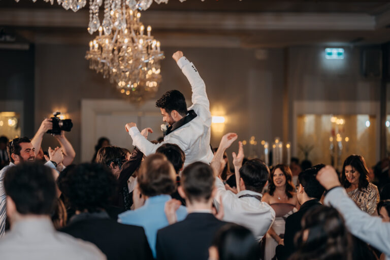 Wedding guests celebrating with raised hands during the lively reception.