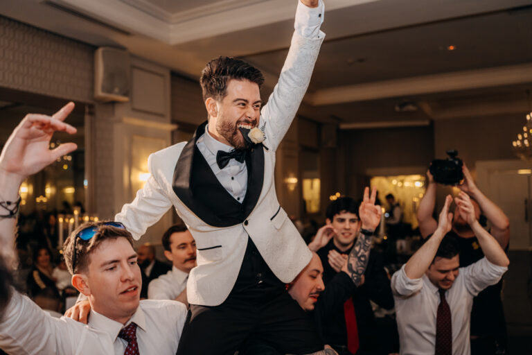 Groom lifted onto guests' shoulders during a lively wedding reception celebration.
