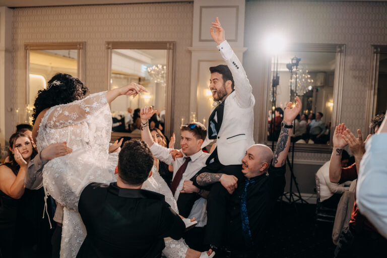 Bride and groom dancing together surrounded by guests at their wedding reception.