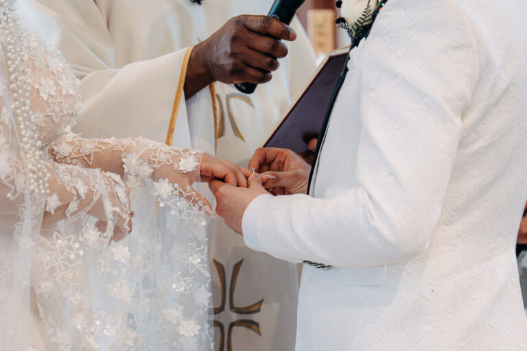 Close-up of the groom placing a wedding ring on the bride's finger during the ceremony.